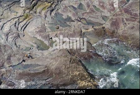 (170325) -- JINJIANG, 25. März 2017 -- Touristen sehen die Überreste des Gezeitenwassers auf Felsen am Meer im Weitou Dorf der Stadt Jinjiang, südöstliche Provinz Fujian, 24. März 2017. ) (Ry) CHINA-FUJIAN-JINJIANG-SEASHORE (CN) ZhangxJiuqiang PUBLICATIONxNOTxINxCHN Jinjiang März 25 2017 Touristen Sehen Sie sich die Überreste von Tidewater AUF Felsen am Meer in Weitou Dorf Jinjiang Stadt Südostchina S Fujian Provinz März 24 2017 Ry China Fujian Jinjiang Seashore CN ZIOCHINXBLINXN Stockfoto