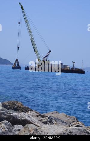 Plattform auf See mit Kran und Hügeln im Hintergrund. Stockfoto