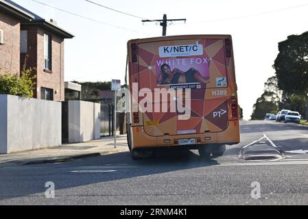 Rückansicht eines von Kinetic Melbourne betriebenen PTV-Bus mit Lackierung von Volgren, der sich an einer Kreuzung dreht und rauchige Abgase abgibt Stockfoto