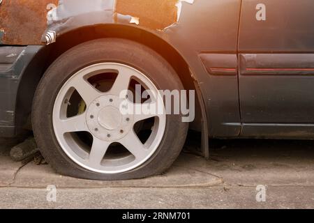 Auto mit Parkplätzen für Platten Reifen im Freien bei heißem Wetter beschädigtes altes defektes Fahrzeug muss gewartet werden Stockfoto