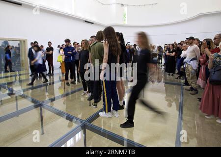 (170515) -- VENEDIG, 15. Mai 2017 -- Künstler treten im Pavillon Deutschlands während der 57. Art Biennale in Venedig, Italien, am 13. Mai 2017 auf. Die deutsche Choreografin Anne Imhof wurde mit dem Goldenen Löwen für die beste nationale Teilnahme an der 57. Art Biennale in Venedig ausgezeichnet. Für ihr Stück Faust nach der klassischen deutschen Geschichte eines Mannes, der seine Seele gegen unbegrenztes Wissen und Macht an den Teufel verkauft, füllte Imhof den weißen, rechteckigen Pavillon Deutschlands mit sich kreuzenden Glaswänden und -Böden. und dann eine Gruppe von Künstlern im Keller platziert. Besucher beobachten die Künstler Stockfoto