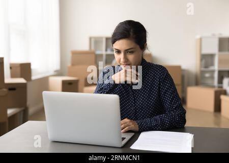 Ernsthafte, schöne indische Geschäftsfrau, die an einem Internet-Store-Startup arbeitet Stockfoto
