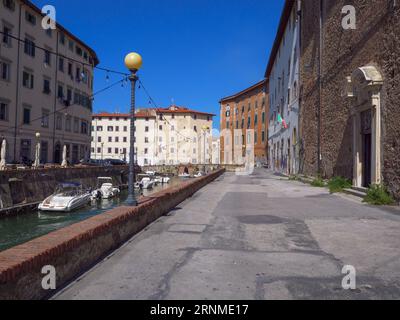 Werfen Sie einen Blick auf ein typisches Livorno-Viertel in der Toskana mit Wasserstraßen im venezianischen Stil und kleinen Motorbooten entlang der Seiten, Italien/ Stockfoto