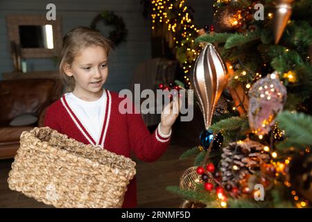 Glückliches entzückendes kleines Kindermädchen, das Weihnachtsbaum dekoriert. Stockfoto