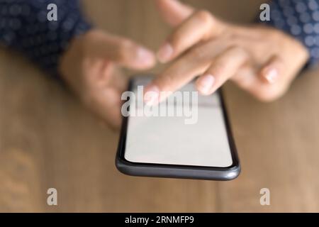 Bildschirm des Mobiltelefons in weiblichen Händen über der Tischoberfläche Stockfoto