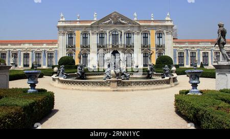 Zeremonielle Fassade des Queluz-Nationalpalastes aus dem 18. Jahrhundert, Neptunbrunnen in den gepflegten hängenden Gärten im Vordergrund, Queluz, in der Nähe von Lissabon Stockfoto