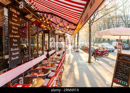 Paris, Frankreich - 24. Januar 2022: Allgemeiner Straßenblick von Paris, der französischen Hauptstadt. Castel Cafe Sitzplätze im Freien mit rot-weiß gestreiftem Schattenzelt Stockfoto