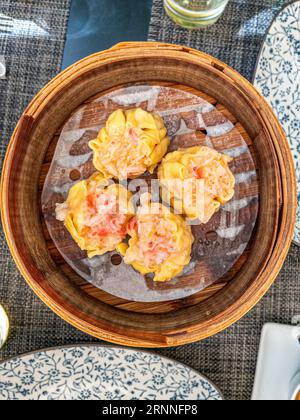 Krabben und Garnelen Shumai (sui mai) Dim Sum serviert in Bambusdampfer. Stockfoto