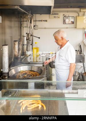 Churrero (Churro-Hersteller), der Churros in Churreria Ana, einem Kiosk auf dem Plaza de la Libertad in Cadiz, Andalusien, herstellt. Stockfoto