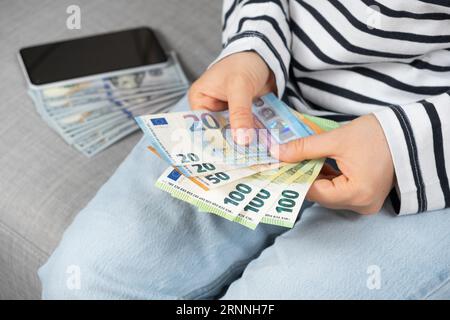 Eine Frau zählt Euro, Dollar im Hintergrund. Stockfoto