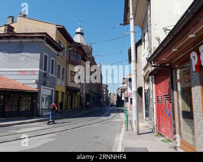 Motorroller-Fahrt auf einer farbenfrohen Straße mit Straßenbahnschienen in der Stadt Sarajevo, Bosnien und Herzegowina, 2. September 2023 Stockfoto