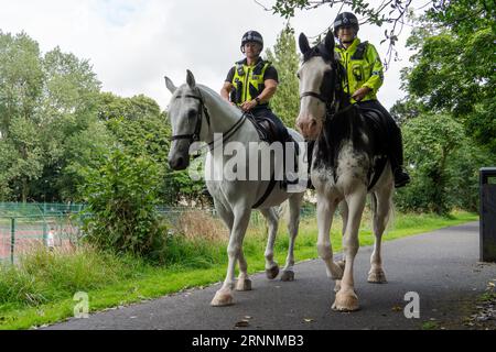 Zwei britische Polizisten zu Pferd in einem öffentlichen Park. Konzept der berittenen Polizei, Polizei, Patrouillen, Bobbys auf dem Schlag, Diensttiere Stockfoto