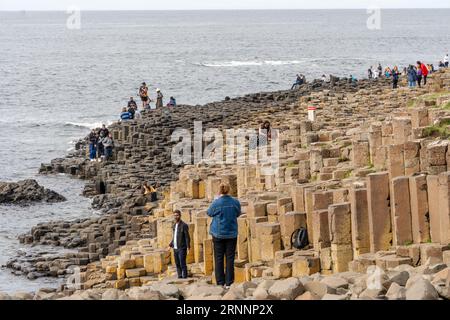 Riesen's Causeway, in der Nähe von Bushmills, Nordirland. Besucher der natürlichen Basalt-Felsformationen, die eine beliebte Touristenattraktion sind. Stockfoto