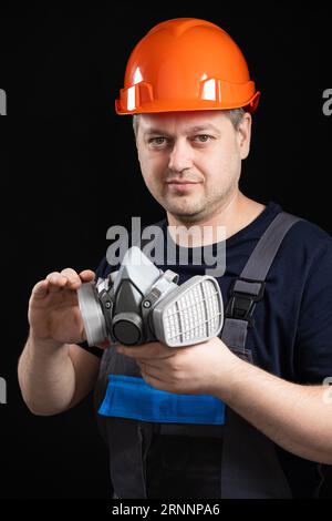 Ein Mann hält eine Atemschutzmaske zum Schutz vor Staub und Gasen. Stockfoto