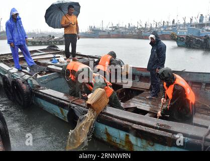 (170730) -- JINJIANG, 30. Juli 2017 -- Polizisten helfen lokalen Fischern, Wasser auf einem Fischerboot an einem Dock in Jinjiang, südöstliche chinesische Provinz Fujian, 30. Juli 2017 abzulassen. Taifun Nesat, der neunte Taifun des Jahres, landete am Sonntagmorgen in Fujian. Der Taifun Haitang, der zehnte Taifun des Jahres, sollte ohne Ruhepause am Sonntagabend im Süden Taiwans landen und am Montagmorgen irgendwo zwischen Xiapu und Jinjiang in der Provinz Fujian eine zweite Landung machen, so das National Meteorological Center. Die beiden Taifune sollten starken Regen und starke Stürme bringen Stockfoto