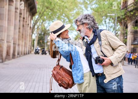 Liebevolles reifes Paar, das sich umarmt und in romantischer Atmosphäre im Freien in der Stadt betrachtet. Fröhlich im Ruhestand. Stockfoto