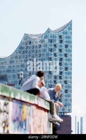Hamburg, Deutschland. September 2023. Vier junge Männer genießen einen sonnigen Tag am Stintfang mit der Elbphilharmonie im Hintergrund. Quelle: Markus Scholz/dpa/Alamy Live News Stockfoto