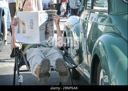 Morecambe, Lancashire - 2. September 2023 - Besucher genossen Morecambes Vintage by the Sea Festival am Samstag. Viele von ihnen kamen in Vintage-Kleidung und ließen die Atmosphäre aufsaugen. Ein Mann erholte sich im Schatten seines Oldtimers und las eine Zeitung, als die Sonne unterging. Quelle: Stop Press Media/Alamy Live News Stockfoto