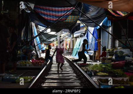(170821) -- MAEKLONG, 21. August 2017 -- Kinder spielen auf der Eisenbahnstrecke, die durch den Maeklong Market in der zentralthailändischen Provinz Samut Songkhram führt, 19. August 2017. Im Maeklong Market, der entlang einer Eisenbahnstrecke gebaut wurde, wird ein Kompromiss zwischen Anbietern und vorbeifahrenden Pendlerzügen erzielt. Wenn die Gleise frei sind, können Standbesitzer nach Belieben Stände einrichten; doch acht Mal am Tag müssen die Markisen und ein Teil der Güter von der Bahn zurückgebracht werden, um Platz für ein- und ausfahrende Züge zu schaffen. Der Geschäftsstil rund um die Zugfahrpläne hat Maeklong Market zu einem der einzigartigsten Märkte gemacht Stockfoto
