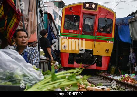 (170821) -- MAEKLONG, 21. August 2017 -- Ein Pendelzug fährt durch den Maeklong Market in der zentralthailändischen Provinz Samut Songkhram, 18. August 2017. Im Maeklong Market, der entlang einer Eisenbahnstrecke gebaut wurde, wird ein Kompromiss zwischen Anbietern und vorbeifahrenden Pendlerzügen erzielt. Wenn die Gleise frei sind, können Standbesitzer nach Belieben Stände einrichten; doch acht Mal am Tag müssen die Markisen und ein Teil der Güter von der Bahn zurückgebracht werden, um Platz für ein- und ausfahrende Züge zu schaffen. Der Geschäftsstil rund um die Zugfahrpläne hat Maeklong Market zu einem der einzigartigsten Märkte in Thailand gemacht. ) (dtf) T Stockfoto