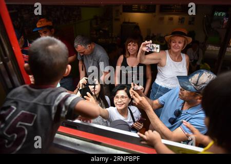 (170821) -- MAEKLONG, 21. August 2017 -- Touristen machen Fotos von einem Pendelzug, der durch den Maeklong-Markt in der zentralthailändischen Provinz Samut Songkhram fährt, 20. August 2017. Im Maeklong Market, der entlang einer Eisenbahnstrecke gebaut wurde, wird ein Kompromiss zwischen Anbietern und vorbeifahrenden Pendlerzügen erzielt. Wenn die Gleise frei sind, können Standbesitzer nach Belieben Stände einrichten; doch acht Mal am Tag müssen die Markisen und ein Teil der Güter von der Bahn zurückgebracht werden, um Platz für ein- und ausfahrende Züge zu schaffen. Der Geschäftsstil rund um die Zugfahrpläne hat Maeklong Market zu einem der einzigartigsten Märkte gemacht Stockfoto