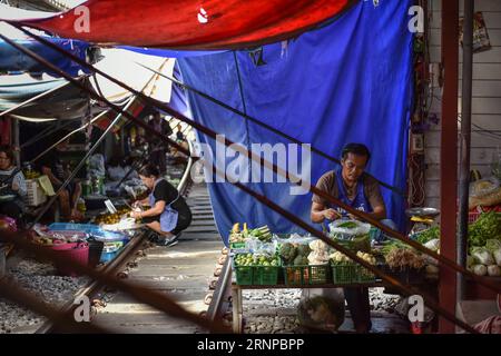 (170821) -- MAEKLONG, 21. August 2017 -- Ein Standbesitzer bereitet sich auf das Geschäft auf dem Maeklong Market in der zentralthailändischen Provinz Samut Songkhram, 19. August 2017 vor. Im Maeklong Market, der entlang einer Eisenbahnstrecke gebaut wurde, wird ein Kompromiss zwischen Anbietern und vorbeifahrenden Pendlerzügen erzielt. Wenn die Gleise frei sind, können Standbesitzer nach Belieben Stände einrichten; doch acht Mal am Tag müssen die Markisen und ein Teil der Güter von der Bahn zurückgebracht werden, um Platz für ein- und ausfahrende Züge zu schaffen. Der Geschäftsstil rund um die Zugfahrpläne hat Maeklong Market zu einem der einzigartigsten Märkte in Thailand gemacht. Stockfoto