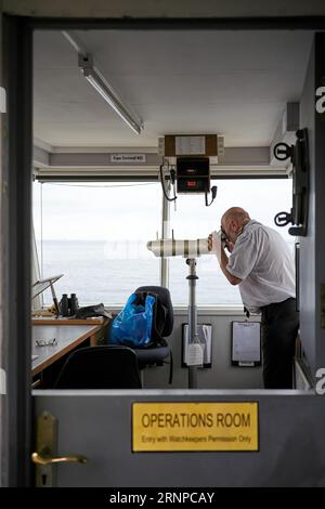 Ein NCI, National Coastwatch Institution, ein Offizier, der in Cape Cornwall über Menschen auf See Ausschau hält. Stockfoto