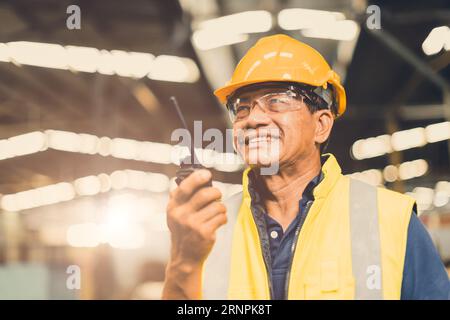 Asiatischer Vorarbeiter, der glücklich ist, Funksteuerung zu verwenden, führt Projektarbeit in der Schwerindustrie-Fabrik durch Stockfoto