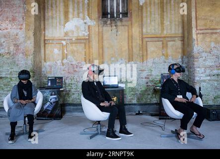(170907) -- VENEDIG, 7. September 2017 -- Regisseur Cai Mingliang (1. R) schaut sich seinen VR-Film The Deserted während des Venedig Film Festivals in Venedig, Italien, 5. September 2017 an. Mit 22 Titeln im Wettbewerb bot das VR-Programm (Virtual Reality) des diesjährigen Filmfestivals in Venedig den Besuchern drei verschiedene Bereiche, um die neue Technologie zu erleben: Erstens ein Kino mit 50 Sitzplätzen, in dem sie Vorführungen auf rotierenden weißen Stühlen genießen konnten, die eine 360-Grad-Ansicht ermöglichten. Zweitens steht oculus auf, um interaktive Werke zu sehen, und schließlich Installationen. Bis zum 4. September wurden ca. 3.000 Besucher registriert Stockfoto