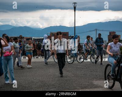 Medellín, Medellin, Antioquia, Kolumbien - Mai 28 2023: Junger Kolumbianer geht in einem öffentlichen Park mit vielen jungen Menschen um ihn herum auf Fahrrädern oder Walki Stockfoto