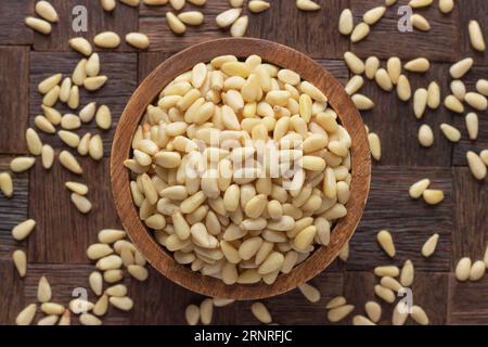 zedernnnüsse in Schüssel auf Holztischhintergrund geschält. Stockfoto