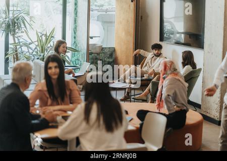 Generationenübergreifende, multiethnische Unternehmensgruppen, die Projektprobleme gemeinsam lösen, während sie in einem modernen Co-Working Space arbeiten Stockfoto