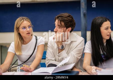Junge Studenten versammelten sich an einem Tisch im Universitätshof und teilten Wissen während der Pause vor der Prüfung Stockfoto