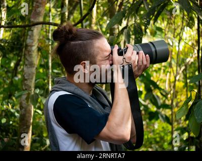 Young White Photographer versucht, Bilder von Vögeln in der Mitte der Natur zu machen Stockfoto