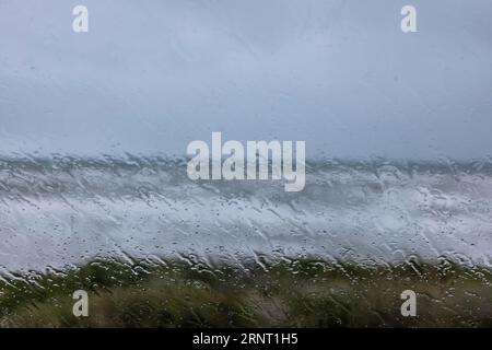 Blick auf das stürmische Meer durch Regentropfen auf einer Fensterscheibe, Portbail, Cotentin, Manche, Normandie, Frankreich Stockfoto