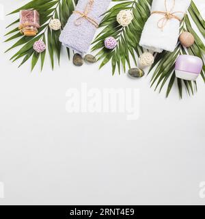 Hochwinkel Blick Spa Steine Handtücher Feuchtigkeitsspendende Creme Peeling Flasche hinterlässt weißen Hintergrund Stockfoto