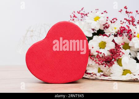 Geschenkbox in Herzform mit Blumenstraußtisch Stockfoto