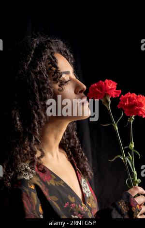 Zarte ethnische Frau mit Blumen Dunkelheit Stockfoto