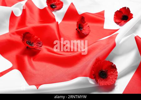 Mohnblumen auf der Flagge Kanadas als Hintergrund. Gedenktag Stockfoto