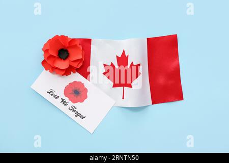 Mohnblumen, Flagge von Kanada und Karte mit Text, DAMIT WIR NICHT auf blauem Hintergrund VERGESSEN. Gedenktag Stockfoto