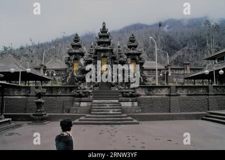 (171202) -- BALI, 2. Dez. 2017 -- Ein Mann spaziert am leeren Pura Pasar Agung-Tempel, bedeckt mit vulkanischer Asche vom Ausbruch des Mount Agung im Dorf Sebudi in Karangasem, Bali, Indonesien, 2. Dez. 2017. ) (zf) INDONESIEN-BALI-VULKAN Kurniawan PUBLICATIONxNOTxINxCHN Stockfoto