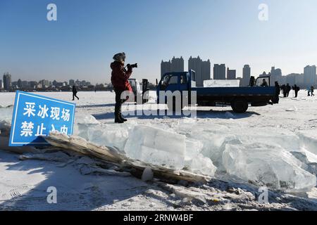 (171203) -- HARBIN, 3. Dezember 2017 -- Ein Fotograf fotografiert Arbeiter, die Eis vom gefrorenen Songhua-Fluss in Harbin, der Hauptstadt der nordöstlichen Provinz Heilongjiang, schneiden, 3. Dezember 2017. Im kommenden Monat werden die Arbeiter Eiswürfel vom gefrorenen Songhua River sammeln, um sich auf den Bau der Eis- und Schneelandschaft vorzubereiten, in der Eisgebäude von bunten Lichtern beleuchtet werden. ) LB) CHINA-HEILONGJIANG-HARBIN-ICE COLLECTION (CN) WangxJianwei PUBLICATIONxNOTxINxCHN Stockfoto