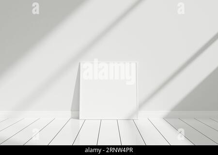 Minimalistisches und sauberes, quadratisches weißes Poster oder Fotorahmen-Mockup auf dem Boden, das mit Schatten an die Zimmerwand lehnt Stockfoto