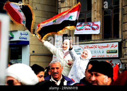 (171221) -- ALEPPO (SYRIEN), 21. Dezember 2017 -- während der Jubiläumsfeier der Befreiung Aleppos auf dem Saadallah-al-Jabiri-Platz in Aleppo, Nordsyrien, am 21. Dezember 2017 schwenken Menschen syrische Nationalflaggen. Die Jubiläumsfeier beinhaltete auch eine Militärparade und die Familien der Märtyrer, die während des Krieges ihr Leben verloren haben, indem sie Plakate mit Fotos ihrer getöteten Söhne und Verwandten hochhielten. Die Schlacht von Aleppo im vergangenen Jahr war ein Wendepunkt im Verlauf der Maßnahmen in der Syrienkrise, aufgrund der strategischen Bedeutung der Stadt, die das wirtschaftliche Zentrum war Stockfoto