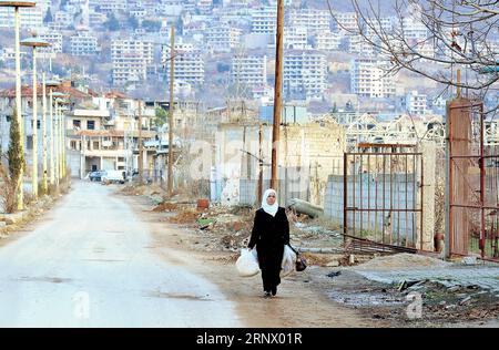 (180106) -- DAMASKUS, 6. Januar 2018 -- Eine Frau geht am 6. Januar 2018 in einer Straße in der vom Krieg verwüsteten Stadt Zabadani, nordwestlicher Landschaft von syrischem Damaskus in der Nähe der libanesischen Grenze. Insgesamt sind 1.500 Familien in die Stadt Zabadani in der nordwestlichen Landschaft der Hauptstadt Damaskus nahe der libanesischen Grenze zurückgekehrt, berichtete die staatliche Nachrichtenagentur SANA am Samstag. Die zurückkehrenden Familien sind Teil von 10.000 anderen, die aus Zabadani geflohen waren, als die Kämpfe dort wüteten, bevor die syrische Armee sie und die umliegenden Gebiete im April 2017 wieder einnahm, nachdem ein Abkommen für die Evakuierung von Th geschlossen wurde Stockfoto