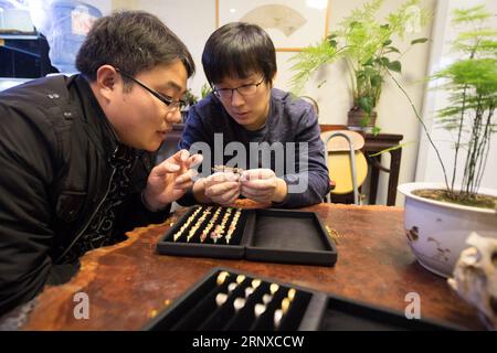 (180122) -- HANGZHOU, 22. Januar 2018 -- Qian Zhongshu (R) diskutiert mit einem Freund in seinem Atelier in Hangzhou, der Hauptstadt der ostchinesischen Provinz Zhejiang, am 22. Januar 2018 die Schmuckgestaltung. Qian wurde 1983 in Hangzhou geboren. Als Enthusiast der traditionellen chinesischen Kultur trat der Absolvent der China Academy of Art aus dem Amt zurück und eröffnete vor etwa neun Jahren sein eigenes Schmuckstudio. Bis jetzt hat seine Gruppe fast 20 Mitglieder. Sie können jedes Jahr mehr als 300 Schmuckstücke herstellen. )(mcg) CHINA-HANGZHOU-SCHMUCKHERSTELLER (CN) WengxXinyang PUBLICATIONxNOTxINxCHN Stockfoto