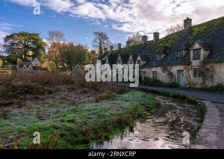 Dies ist ein Blick auf Bibury Town, eine berühmte traditionelle englische Stadt an einem kalten Wintermorgen mit frostigem Gras in der Cotswolds Landschaft am 0. Januar Stockfoto