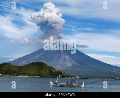 (180128) -- PEKING, 28. Januar 2018 -- Ein Fischerboot segelt, als der Vulkan Mayon in der Provinz Albay, Philippinen, ausbricht, 25. Januar 2018. Mehr als 70.000 Menschen haben die unmittelbare Gefahrenzone um den ausbrechenden Mayon-Vulkan auf den Philippinen verlassen, aber immer noch weigern sich viele Dorfbewohner, hauptsächlich Männer, ihre Häuser zu verlassen, um ihre Farmen und Nutztiere zu schützen. ) (rh) XINHUA PHOTO WEEKLY CHOICES ROUELLExUMALI PUBLICATIONxNOTxINxCHN Stockfoto