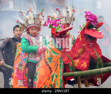 (180223) -- LIPING, 23. Februar 2016 -- die Teilnehmer tragen Kinder in traditioneller Schutzkleidung auf Limousinenstühlen, um durch das Dorf zu marschieren, während sie singen und tanzen, um für Glück und ein gutes Erntejahr zu beten, während einer Vorstellung zum fest der traditionellen Volksgruppe der Dong, Tai Guan Ren, im Dorf Huanggang von Liping County, Qiandongnan Miao und die autonome Präfektur Dong, Provinz Guizhou im Südwesten Chinas, 22. Februar 2018. Tai Guan Ren, was bedeutet, den Friedensgesandten und Glücksgesandten zu tragen, ist ein jährliches Dong-Volksfest, das normalerweise zu Beginn des chinesischen Mondneujahrs gefeiert wird Stockfoto