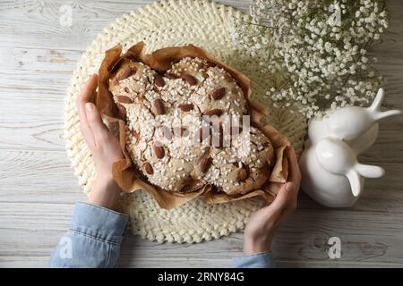 Frau mit köstlichem italienischen Oster-Taubenkuchen (traditionelles Colomba di Pasqua) am weißen Holztisch, Blick von oben Stockfoto